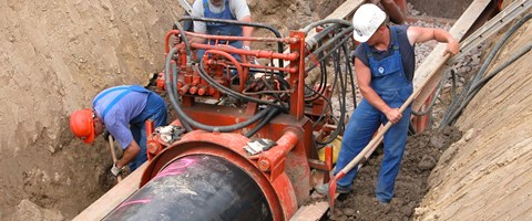 Drei Mitarbeiter arbeiten in einer Baugrube an Rohrleitungen Drei Mitarbeiter arbeiten in einer Baugrube an Rohrleitungen
