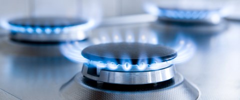 Drei blaue Gasflammen auf einem silbernen Gasherd - Nahaufnahme Drei blaue Gasflammen auf einem silbernen Gasherd - Nahaufnahme