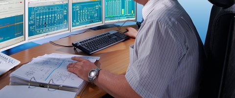 Mitarbeiter an einem Schreibtisch mit mehreren Monitoren Mitarbeiter an einem Schreibtisch mit mehreren Monitoren